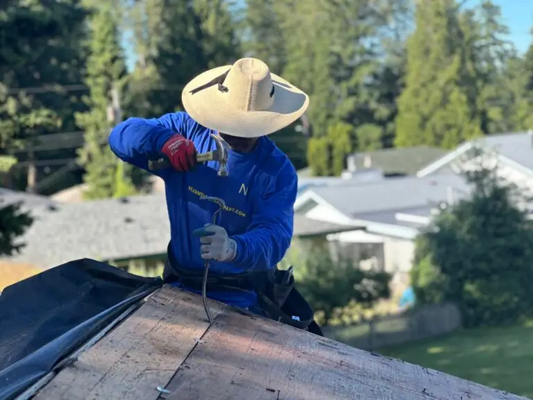 man wearing a blue shirt and white hat fixing a roof