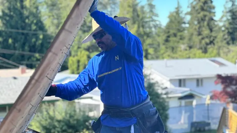 a man in a blue shirt and hat working on a roof