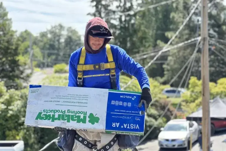 a male roofing expert carrying a box