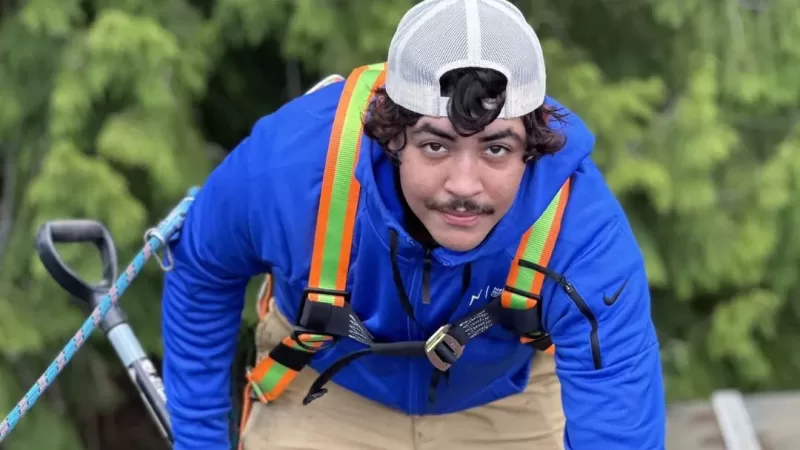 a roofer man in a blue jacket and white cap with a rope