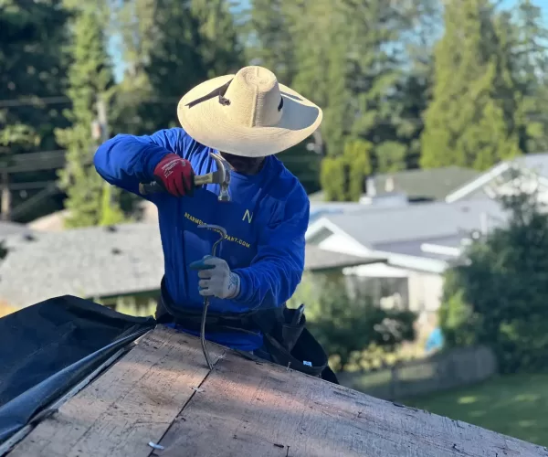 man with a hat working on a roof